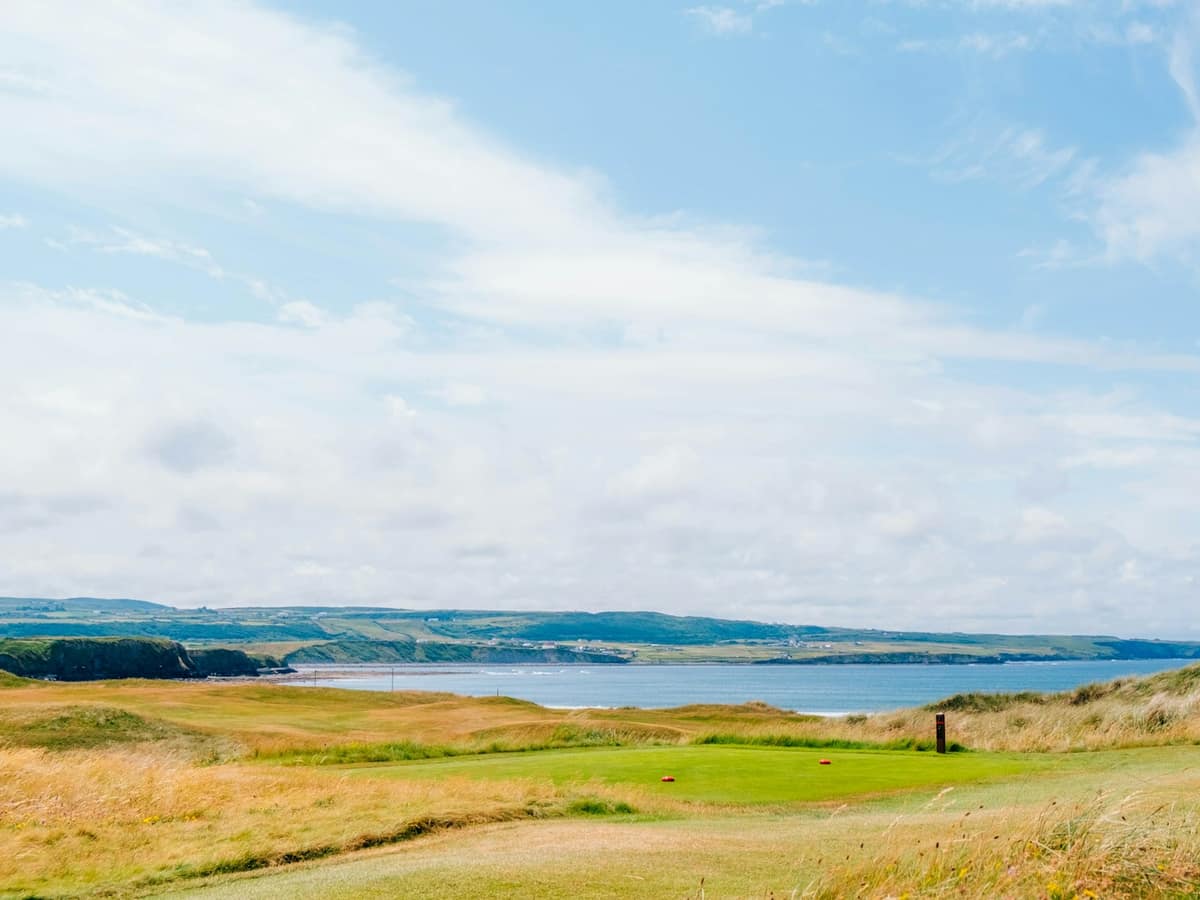 A links golf course running down to the sea under a wide sky